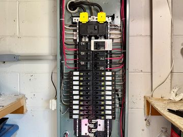 Open electrical panel with circuit breakers and organized wiring inside.