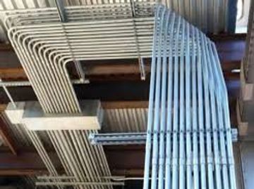 Neatly organized electrical conduit pipes on a ceiling.