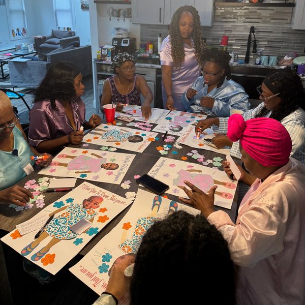 Group of women crafting posters with baby pictures.
