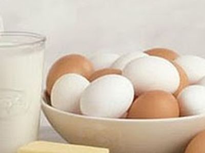 Bowl of white and brown eggs with a glass of milk.