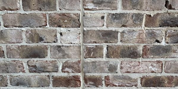 Brick wall with a vertical gap being filled with foam sealant.