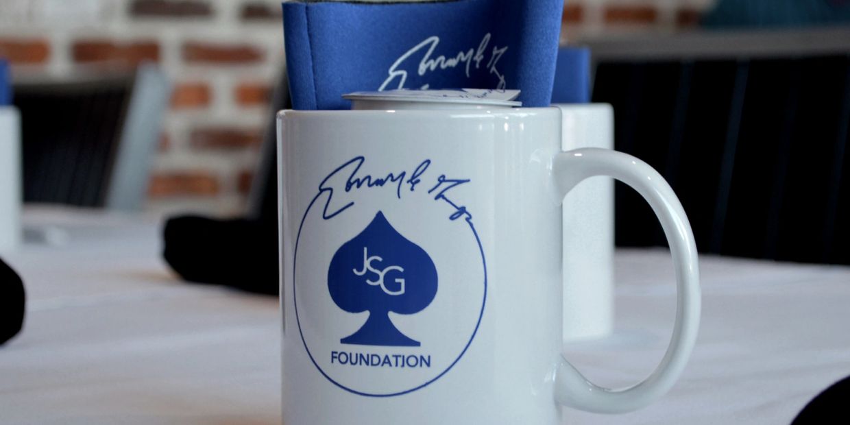 White mug with JSG Foundation logo and blue napkin.