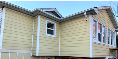 The exterior of a two-story home featuring fresh light-yellow horizontal siding with white trim arou