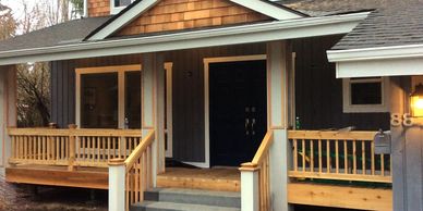 A porch with wooden railings and steps leading to a dark front door.
