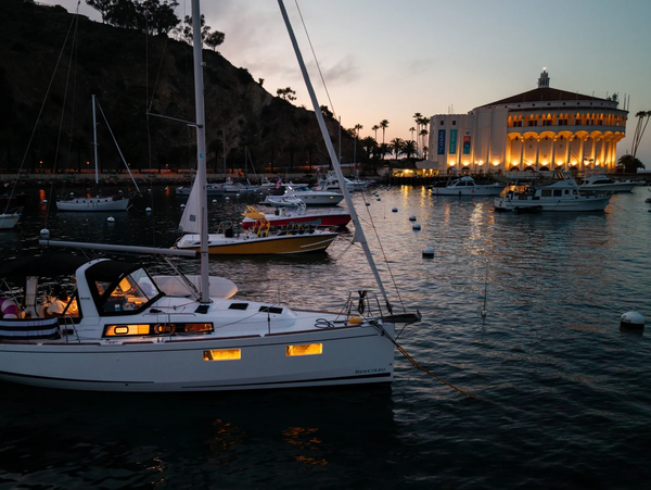 A sailboat moored in Avalon, CA, at dusk with the famous Avalon Casino in the backdrop. 