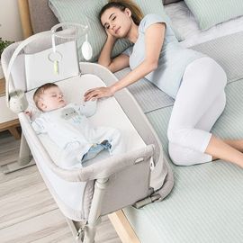 Mother resting beside her baby sleeping in a portable crib.
