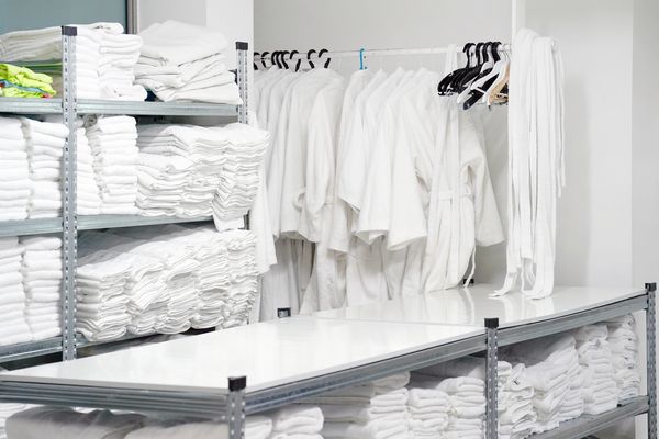 The image depicts a well-organized laundry or linen storage area, likely in a hotel, spa, hospital.