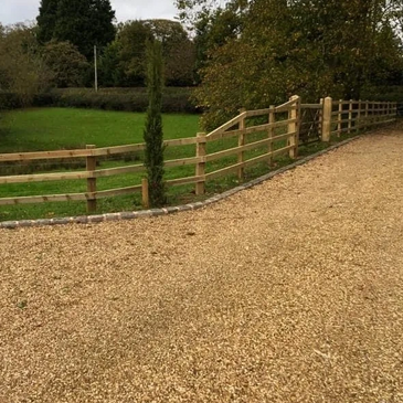 Post and rail fencing along gravel driveway