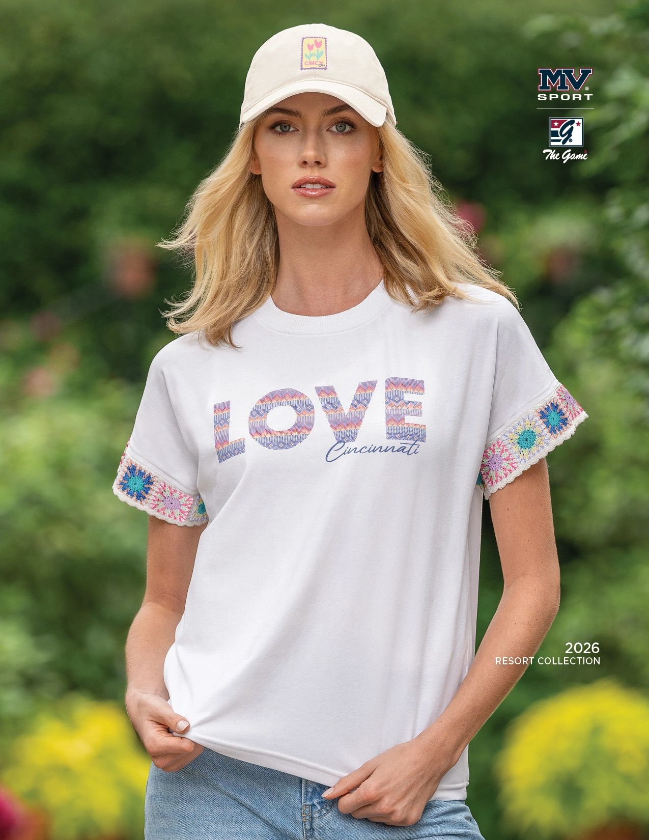Woman wearing a white "LOVE Cincinnati" t-shirt and a light beige cap outdoors.