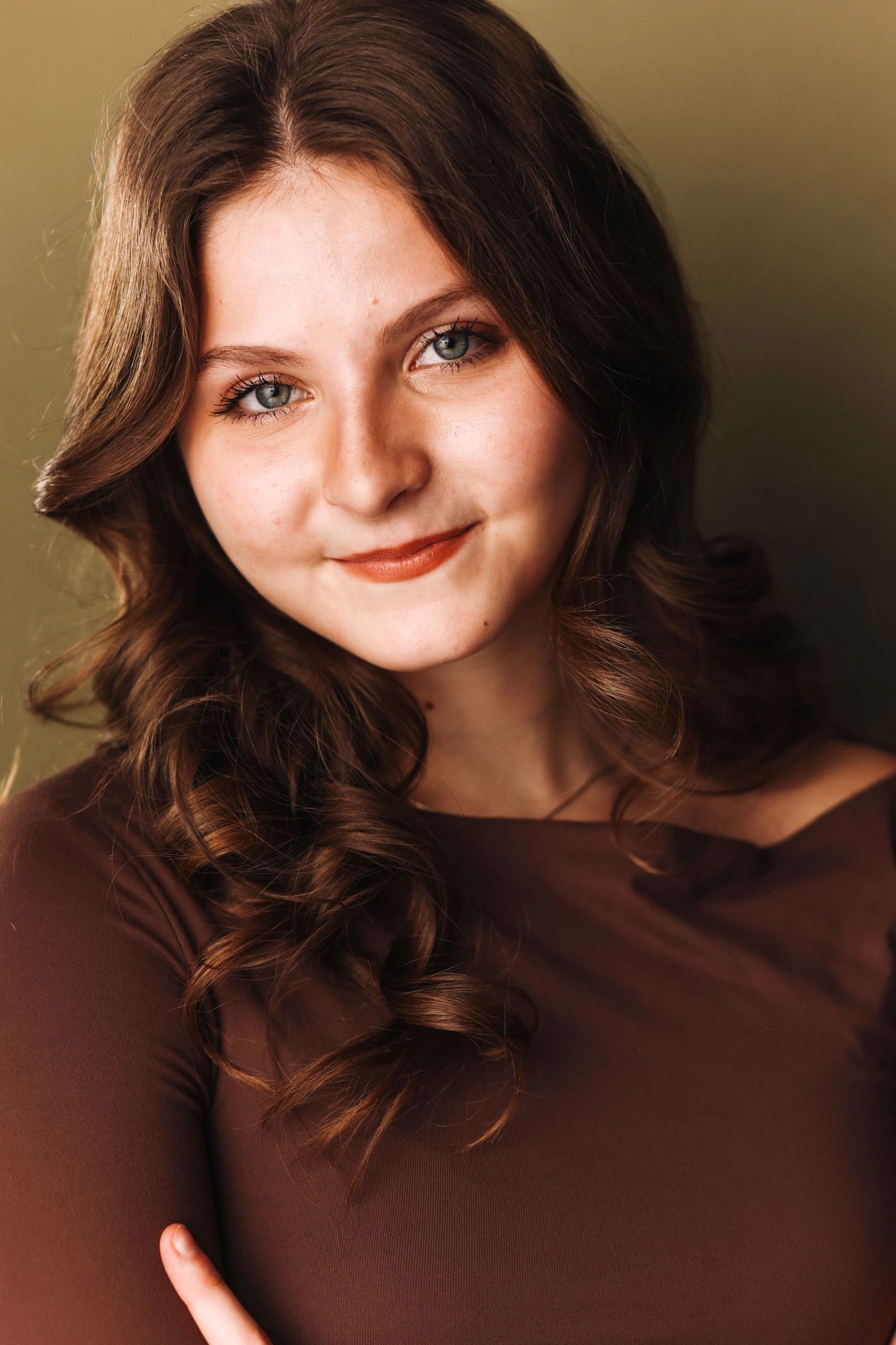 Young woman with curly brown hair and a warm smile.