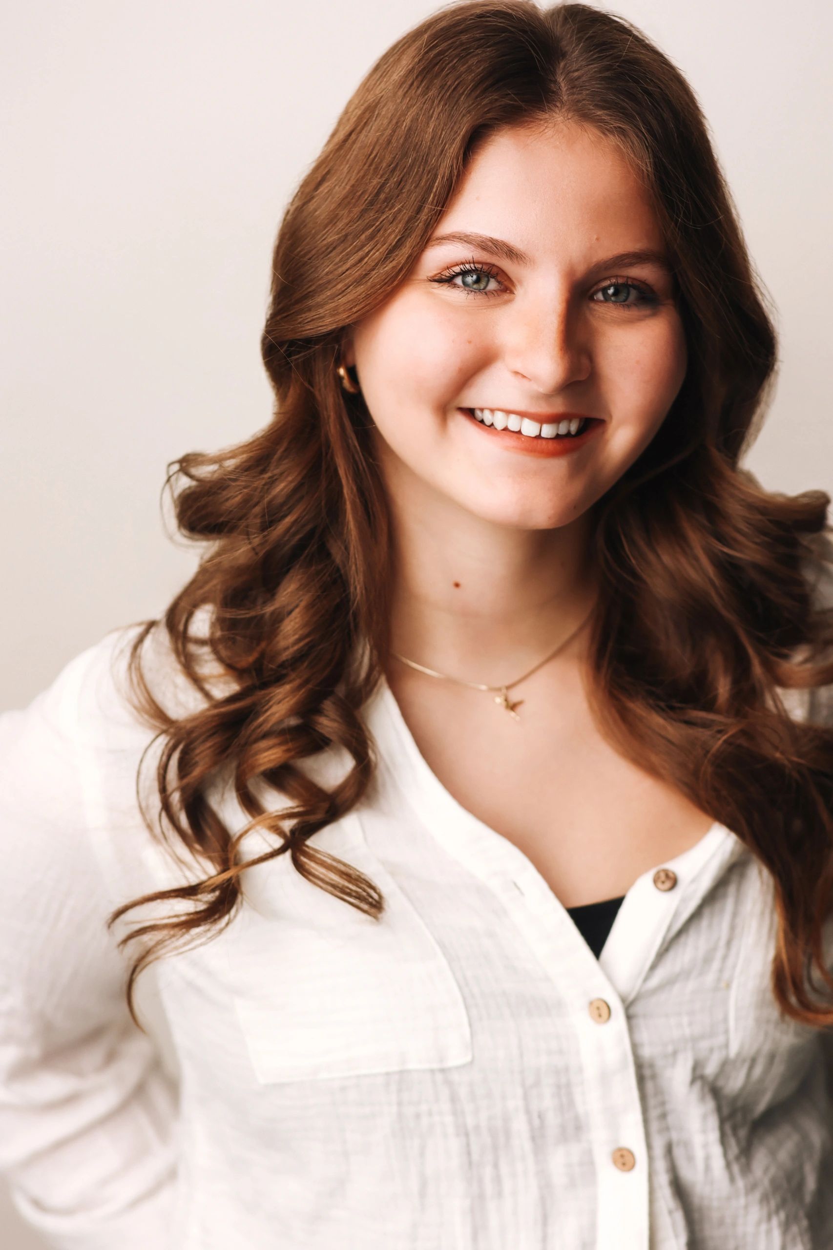 Young woman with curly brown hair smiling warmly.