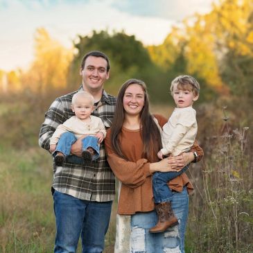 A happy family of four posing outdoors in autumn.