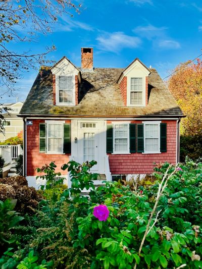 Charming small house with red siding and white trim.