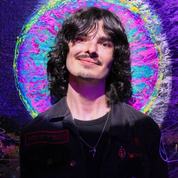 Young man with dark curly hair smiling in front of a vibrant, colorful circular backdrop.