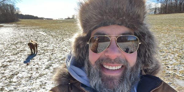Dog in field behind a man smiling