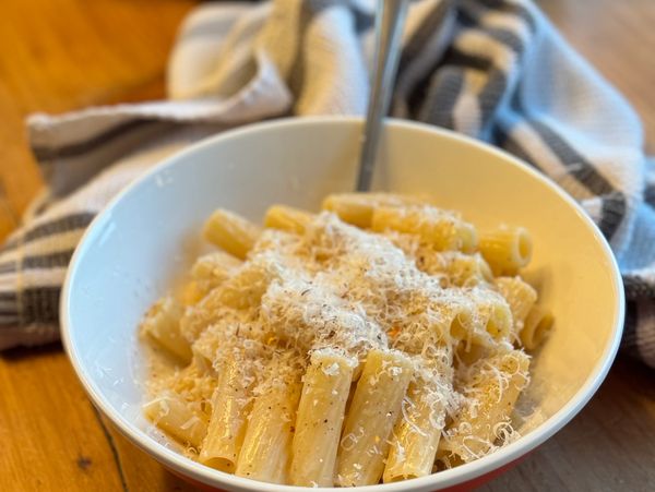 Bowl of rigatoni pasta with grated cheese.