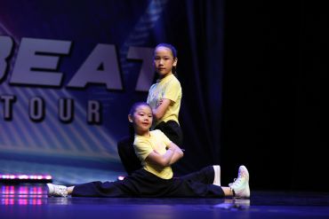 Two young girls performing a dance routine on stage.