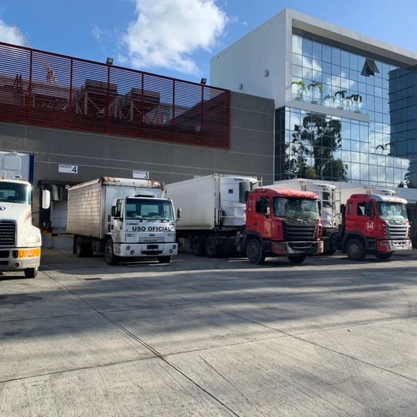 A row of trucks parked outside a modern commercial building.