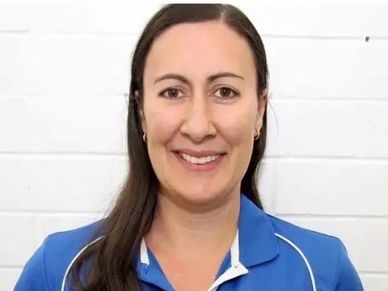 Smiling woman in blue sports shirt with emblem.