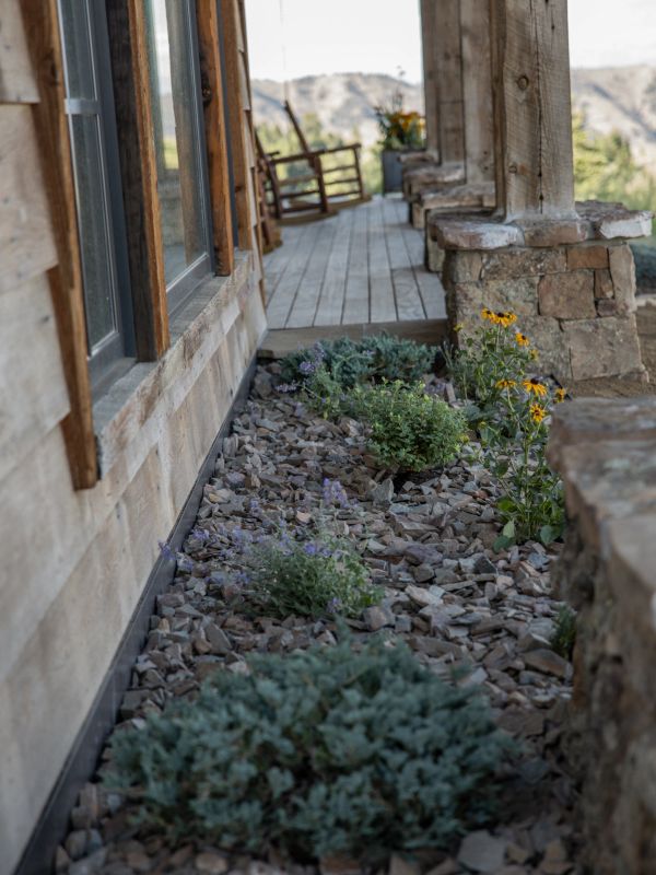 Rock garden with plants beside wooden porch.