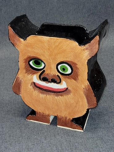 A whimsical ceramic figure with green eyes and a friendly smile.