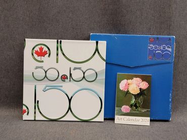 Two vintage 2022 art calendars, one featuring Canadian-themed design.