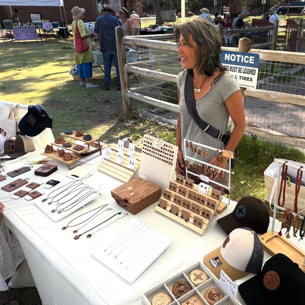 Woman selling handcrafted jewelry and accessories at an outdoor market.