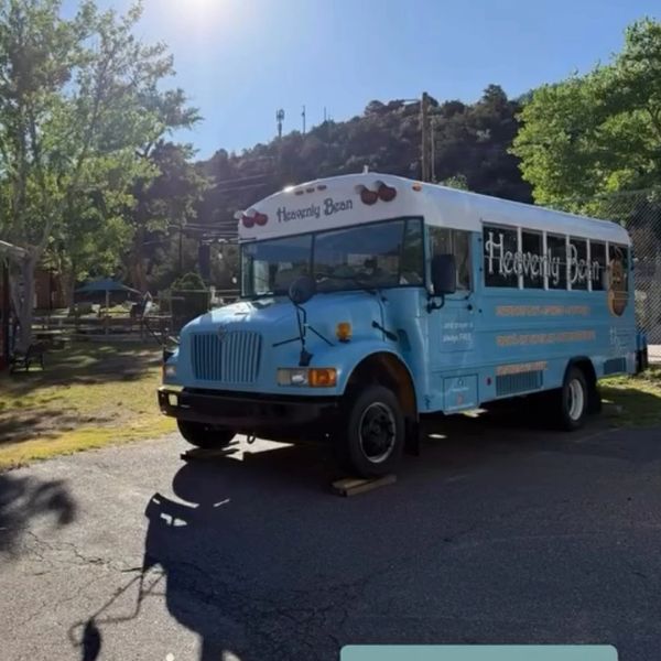 A blue and white bus labeled 'Heavenly Bean' parked on a sunny day.