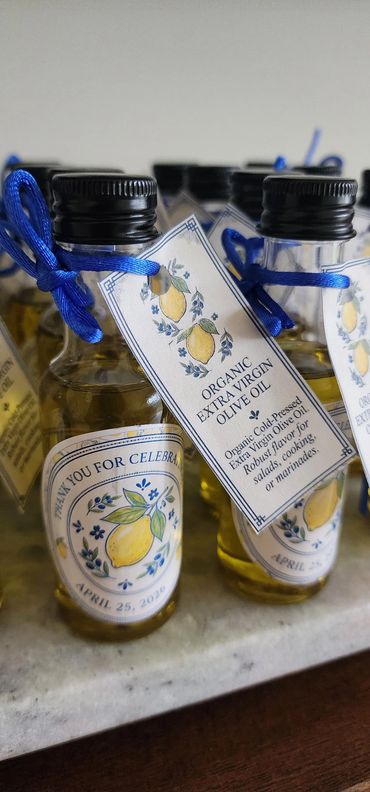 Mini bottles of organic extra virgin olive oil with thank you tags and blue ribbons.