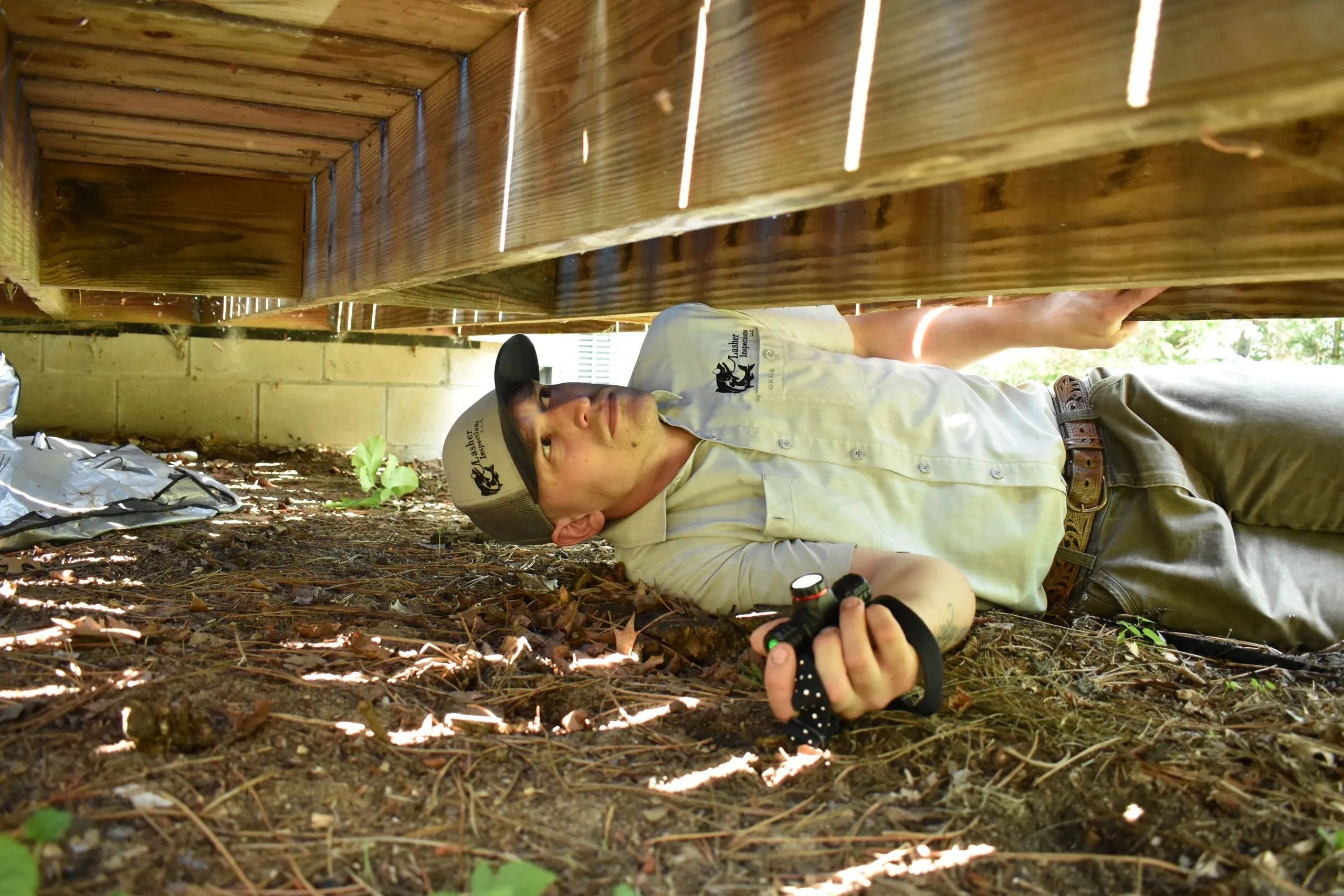 Lasher Inspections inspector crawling under a home to inspect the foundation and crawl space 