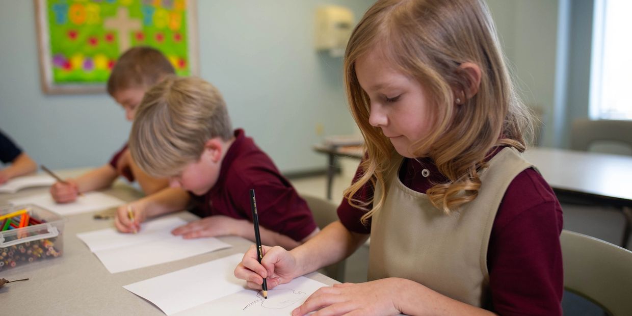 Young children focused on drawing in a classroom setting.
