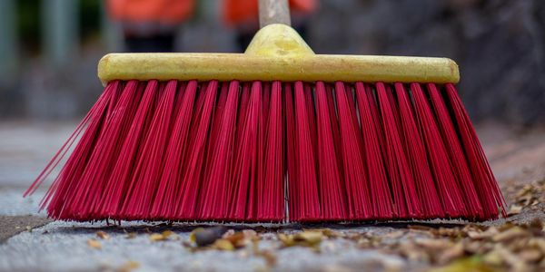 Close-up of a red broom sweeping outdoor ground.