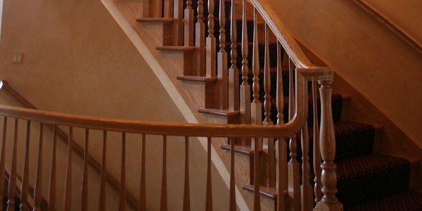 Elegant wooden staircase with curved banister and warm peach walls.