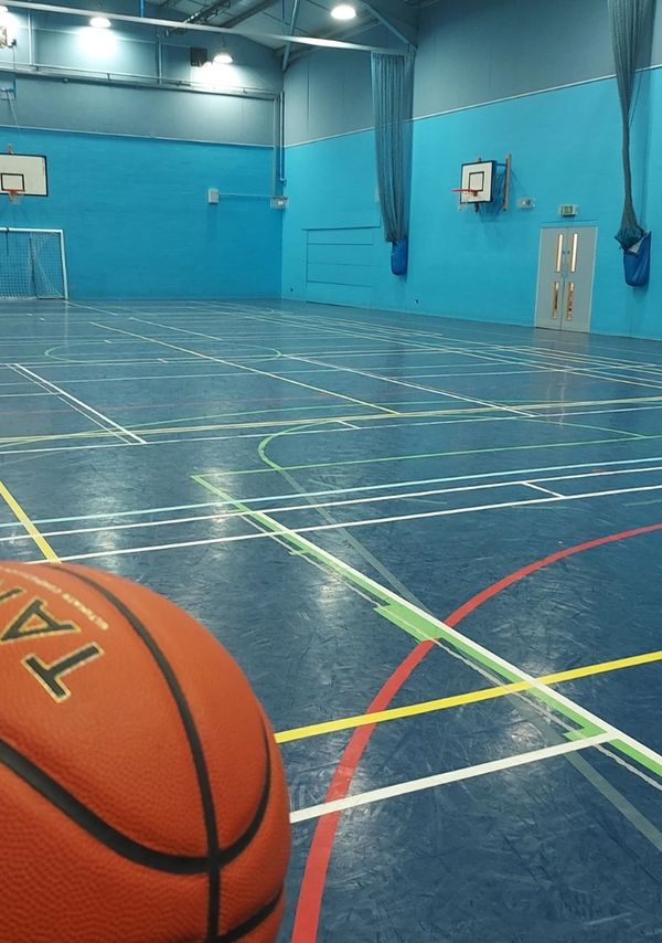 Indoor basketball court with a basketball in the foreground.