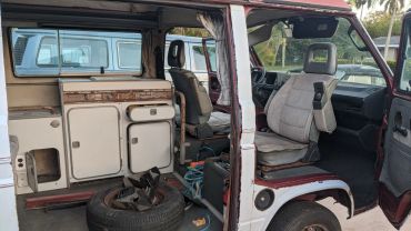 Interior of a vintage van showing seats and a small kitchenette area.