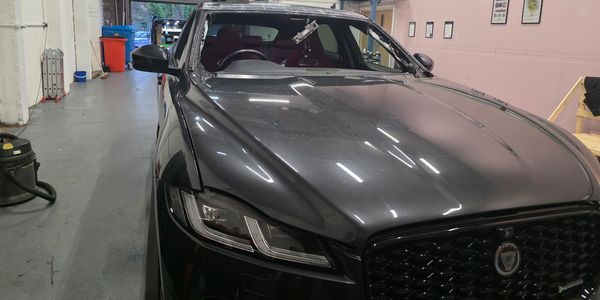 A sleek black Jaguar car parked inside a garage or workshop.