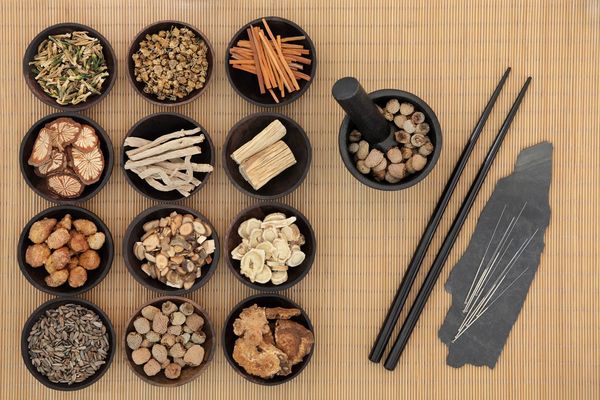 Herbs on dishes next to acupuncture needles.
