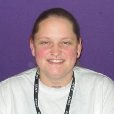 Smiling person with a septum piercing and staff lanyard.