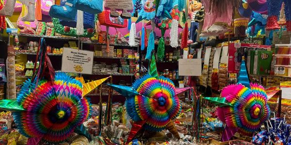 Colorful star-shaped piñatas and baskets of candy in a festive store.