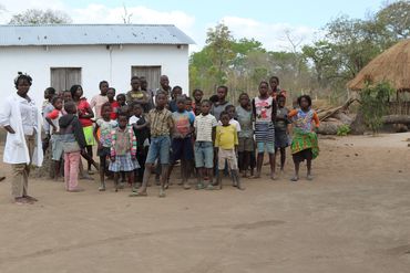 A group of children and adults standing outside near rural houses.