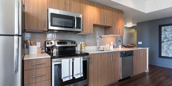 Modern kitchen with stainless steel appliances and wooden cabinetry with staging decor.