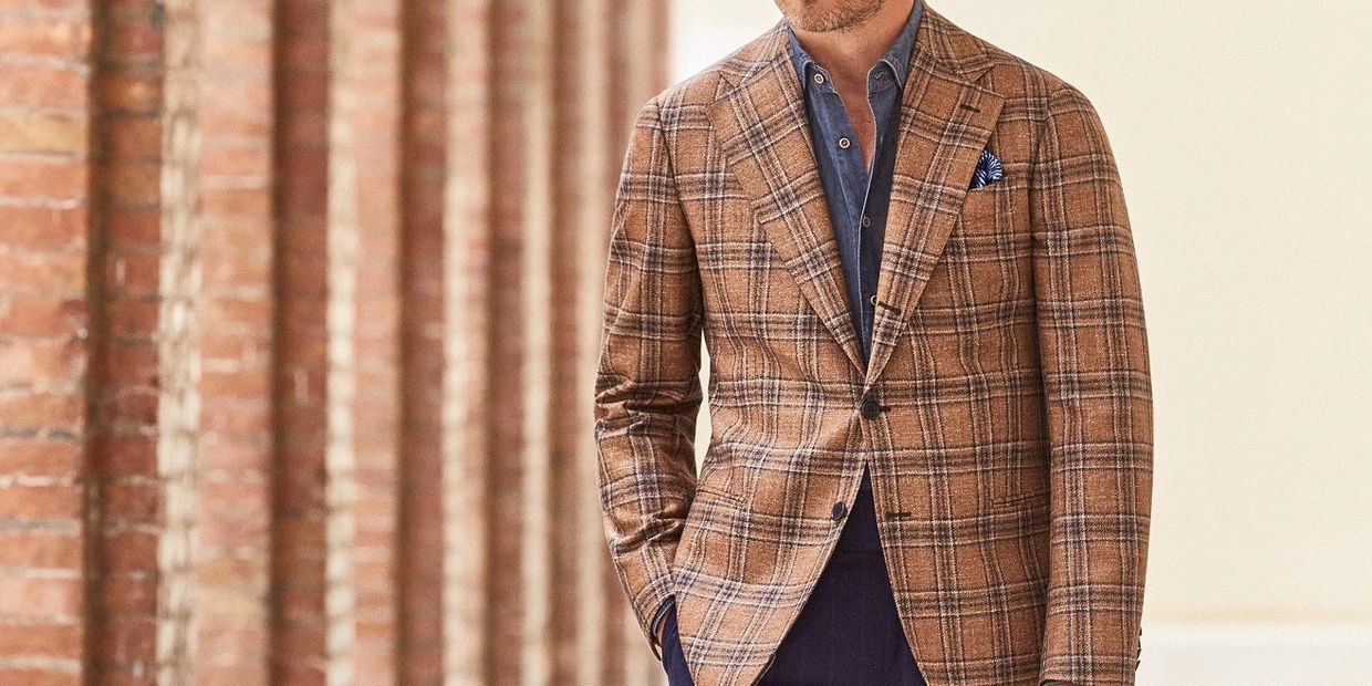 Man wearing a brown plaid blazer with a blue shirt and pocket square.