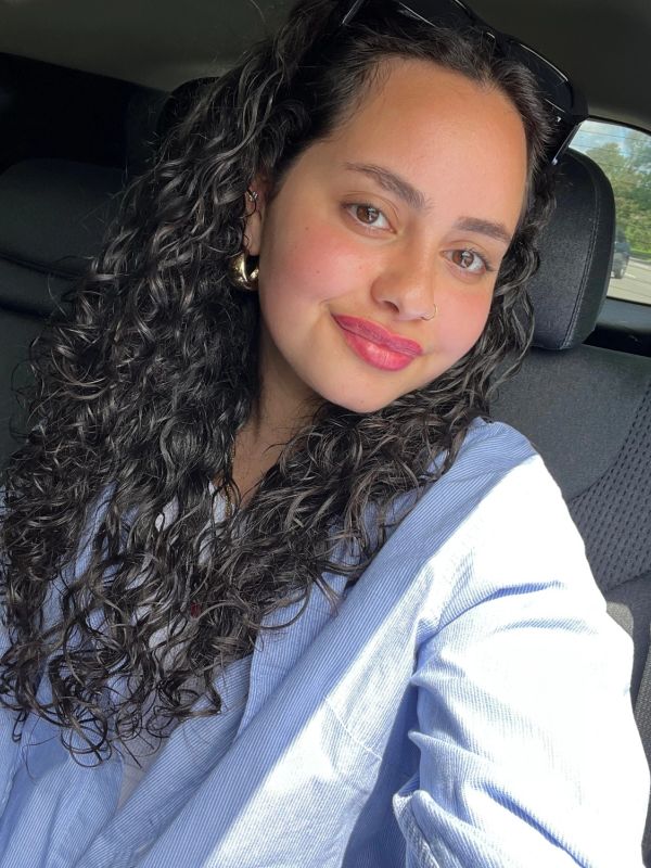 Smiling young woman with curly hair in a car.