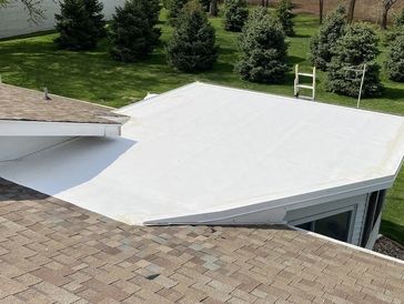 A white flat roof adjoining a shingled sloped roof.