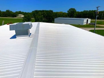 White metal roof on a building with clear blue sky.