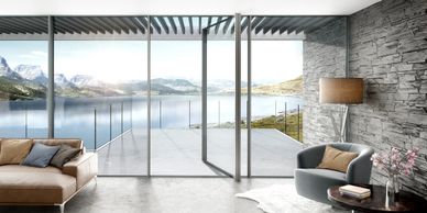 Modern living room with a scenic lake and mountain view through large glass doors.
