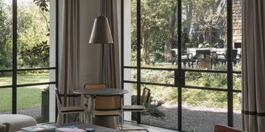 Cozy dining area with large glass windows overlooking a lush garden.