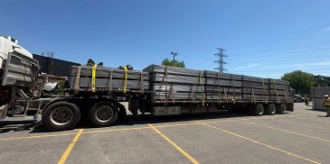 Flatbed truck carrying large steel beams.