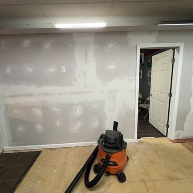 Drywall patching in progress with a shop vacuum on the floor.