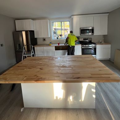 Man working in a modern kitchen with a large wooden island countertop.